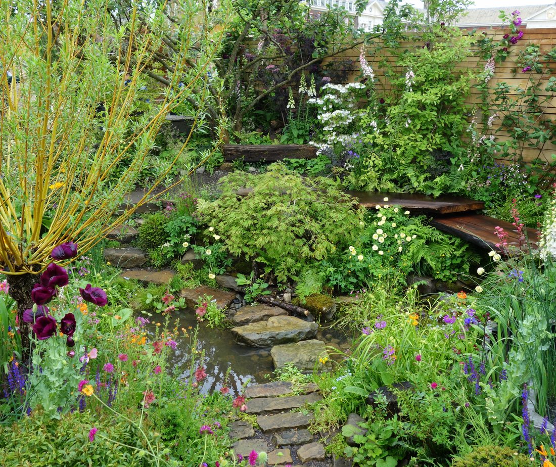 The garden as it could be: a stone path beside water through deep, loose planting